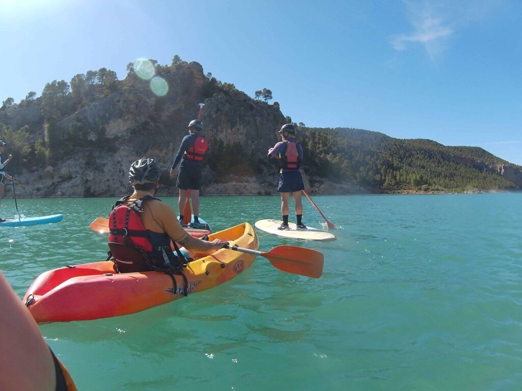 Personas practicando kayak y paddle surf en las Lagunas de Ruidera, una actividad de aventura ideal desde la casa rural La Amorevieta en Pozoamargo, Cuenca